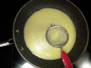 elaborant la salsa pil pil amb un colador