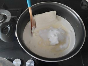paso de elaboración de la tarta de frambuesa, derritiendo y mezclando la nata y el queso crema y el azúcar