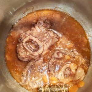 osobuco cuinant-se amb salsa amb herbes aromàtiques, pastanaga, ceba