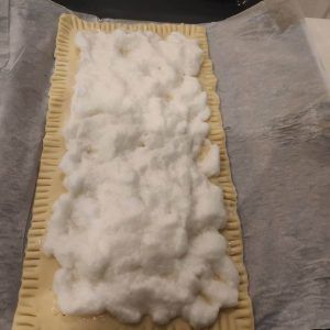 la coca en una bandeja de horno , la masa y encima la clara a punto de nieve