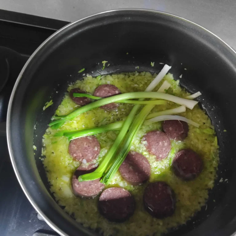 sofriendo ajos tiernos y rodajas de butifarra negra para preparar la receta de habas a al catalana