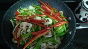 en una sartén cocinandose las verduras en juliana
