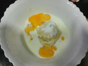 en un bol, huevos ,leche y masa madre para la coca de frutas