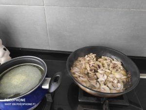 en la sartén friéndose los champiñones y al lado la cazuela de caldo al fuego