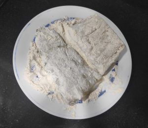 un plat amb dues peces de bacallà enfarinat