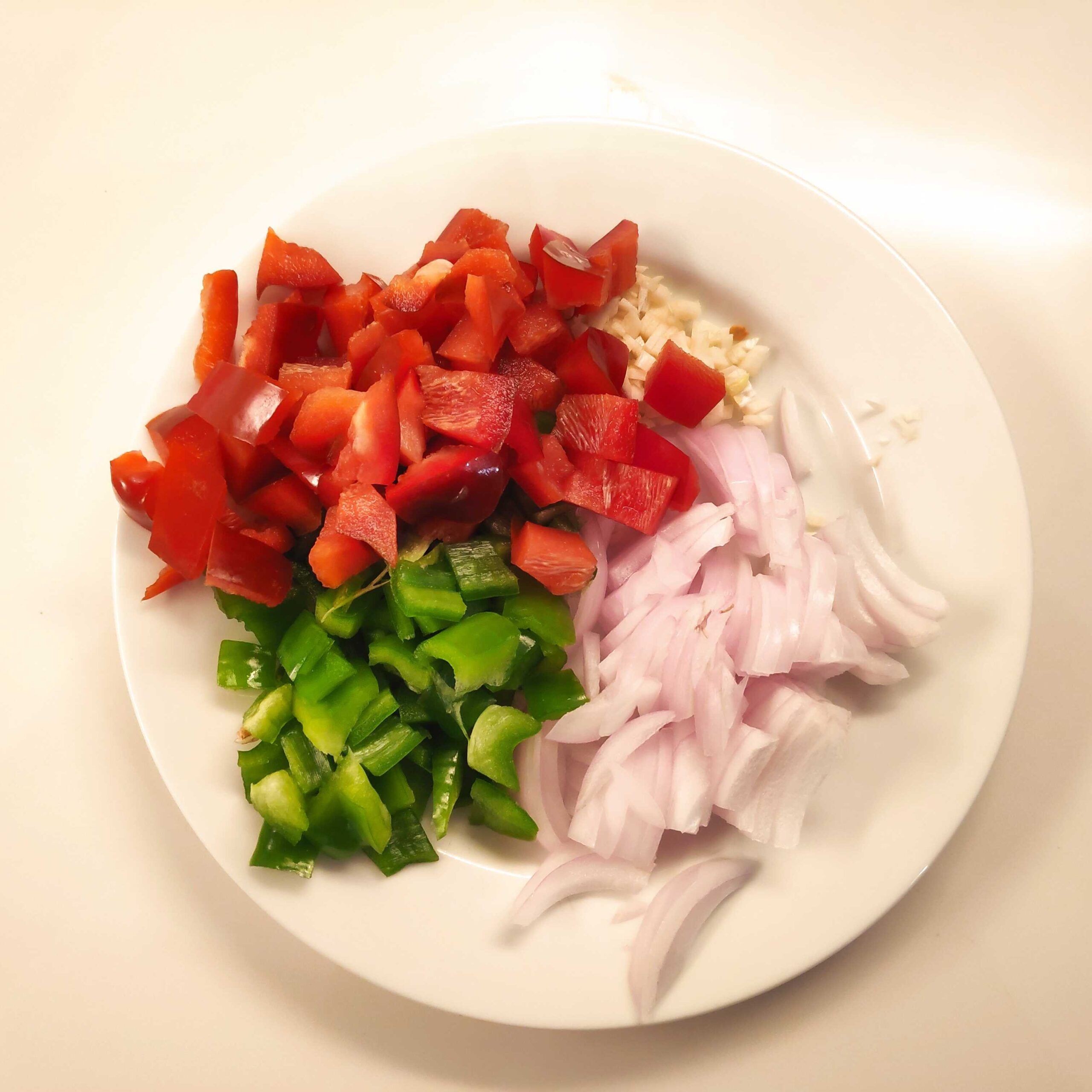 verduras cortadas en un plato , cebolla ajos, y pimiesntos