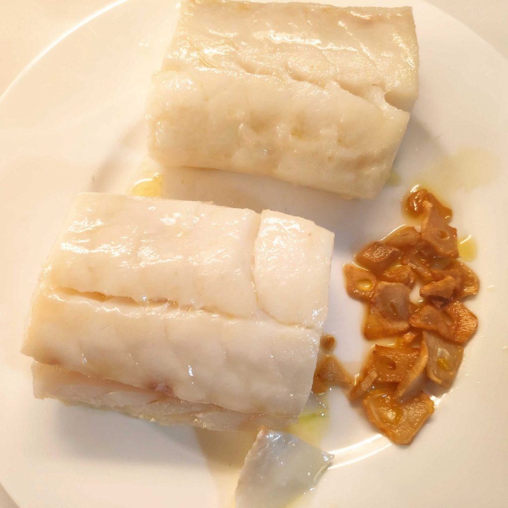 dues porcions de bacallà amb alls laminat en un plat