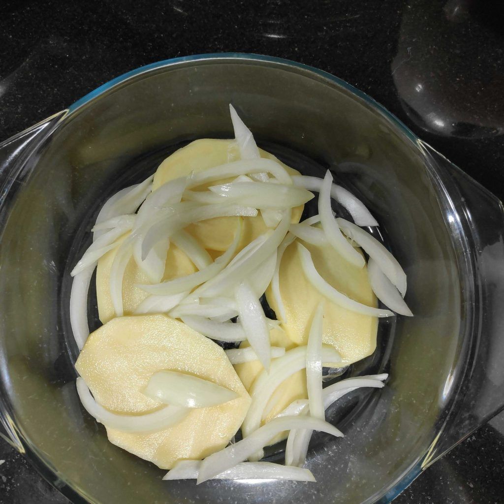 patates i ceba tallades en una font apte per el forn