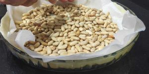 molde con masa de quiché cubierta de papel de horno y alubias haciendo peso para cocer al ciego