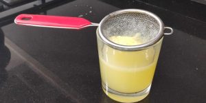 un colador sobre un vaso para colar el zumo de limón
