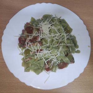 cintas verdes de espinacas con verduras y queso rallado en un plato