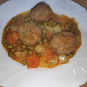 un plato de albóndigas a la jardinera con guisantes y zanahoria