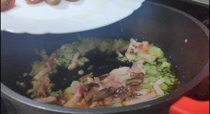 añadiendo anchoa troceada a la cazuela del sofrito