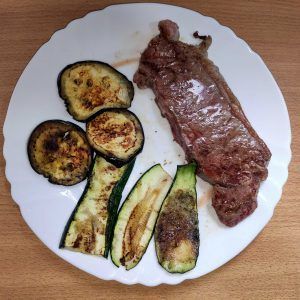 en un plato un entrecot a la plancha con verduras calabacín y berenjena