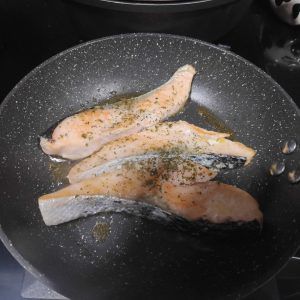 dos escalopines de salmón cocinándose a la plancha
