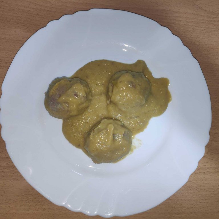 albóndigas en salsa de castañas en un plato blanco sobre fondo de madera