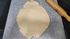 la masa extendida sobre papel de hornear y un rodillo