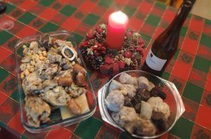 en una taula adornada de Nadal, una espelma, una ampolla de vi i dos recipients amb carn d'olla el plat tradicional