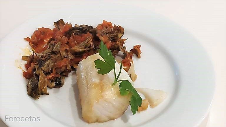 en un plat un llom de bacallà i sofregit de tomàquet i carxofes fregides
