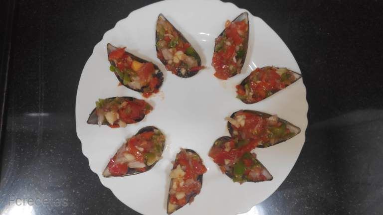 Musclos en pipirrana en un plat, els musclos porten tomàquet, ceba i pebrot a trossets.