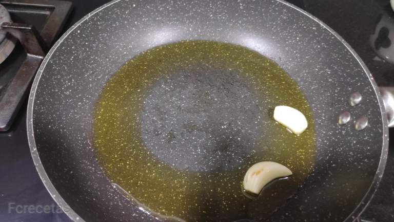 en una sartén aceite y dos ajos pelados