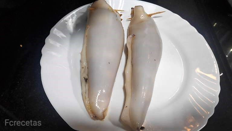 dos calamares rellenos crudos, cerrados con un palillo