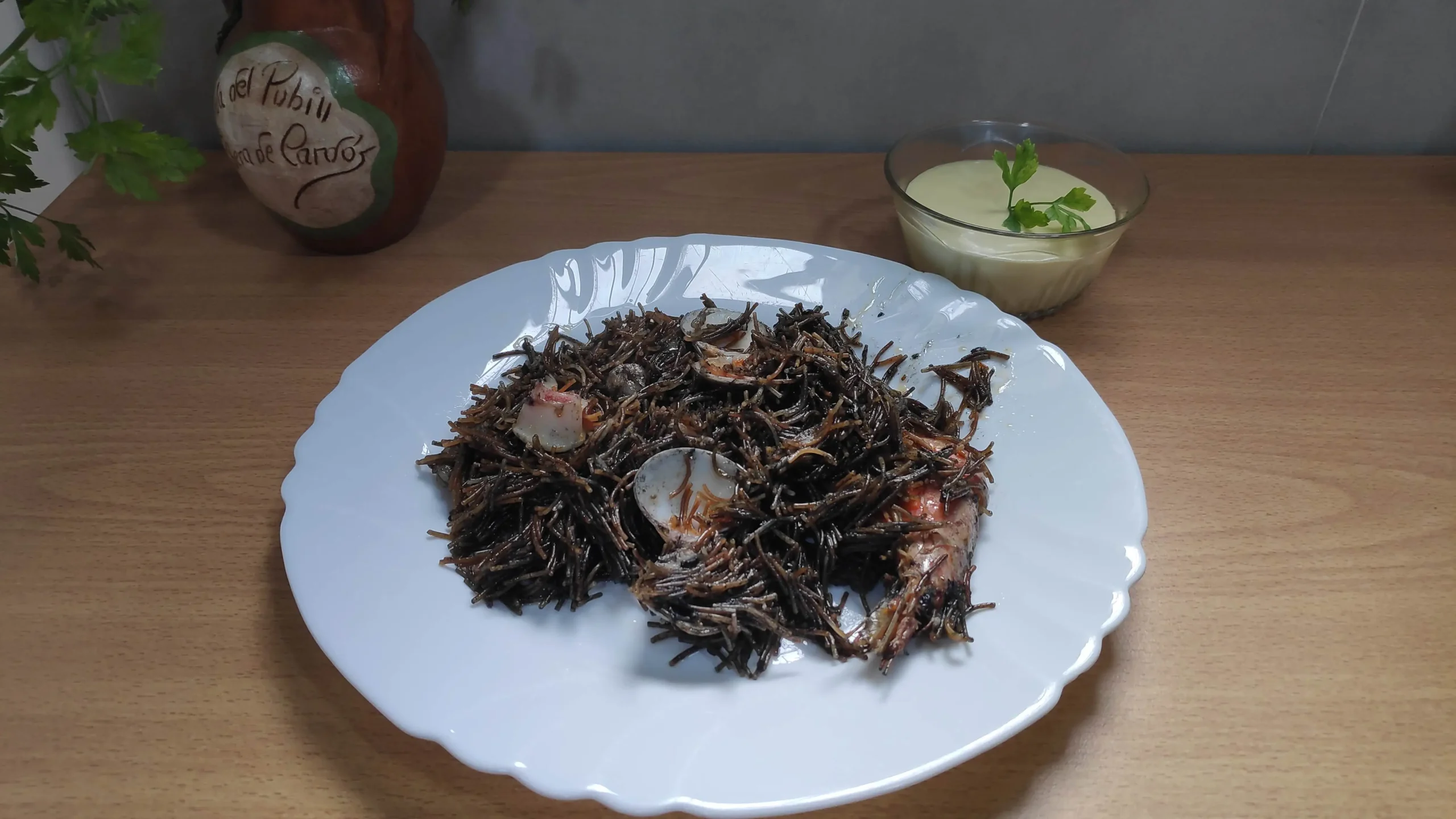Un plato con fideua negra y alioli