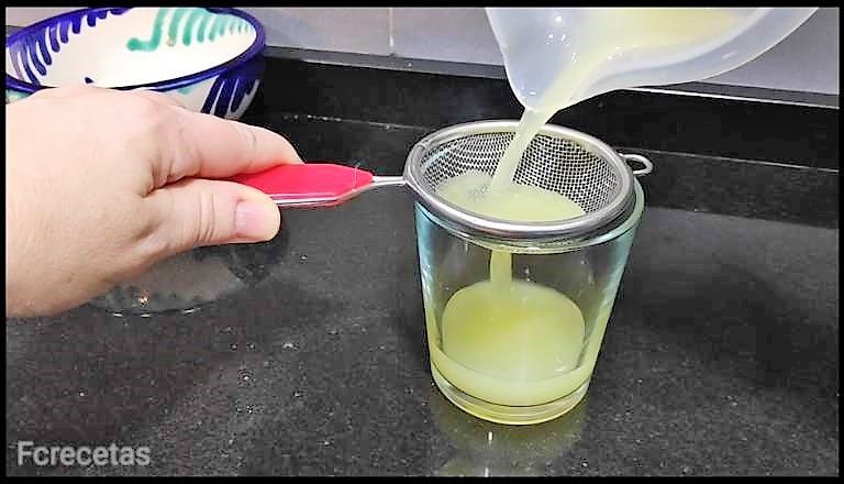 colador colando el zumo de limón en un vaso.