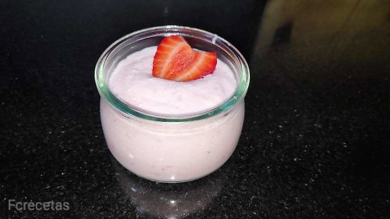 un vasito con espuma de fresa decorado con medio fresón