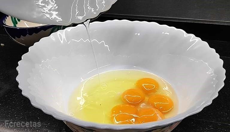 afegint sucre als ous en un recipient blanc