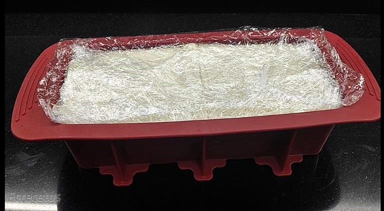 pastís de pa de motlle dins del motlle i embolicat amb film transparent