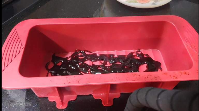 un molde de silicona rojo con caramelo líquido