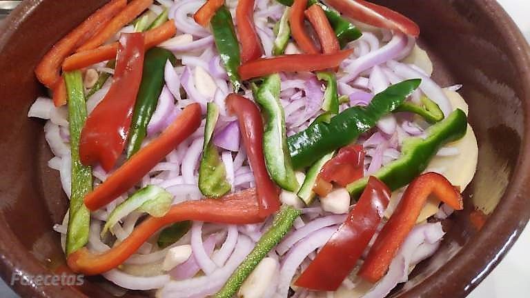 cebolla y pimientos cortados en una cazuela de barro