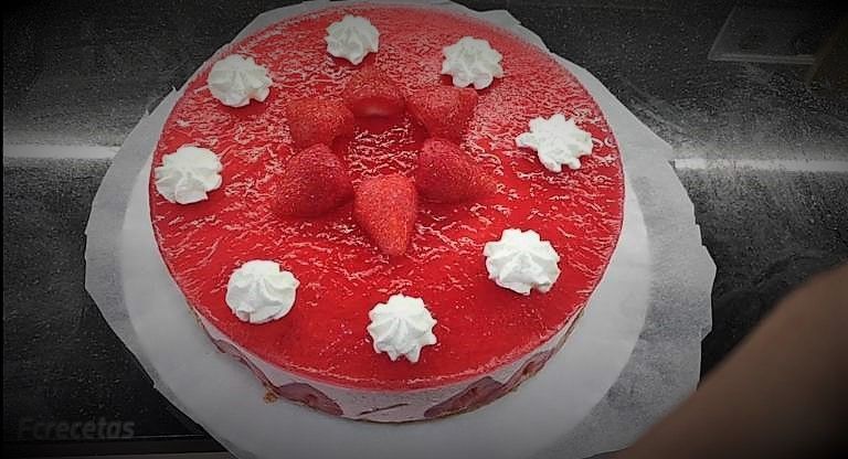 una tarta de mousse de fresosnes decorada con fresones y nata