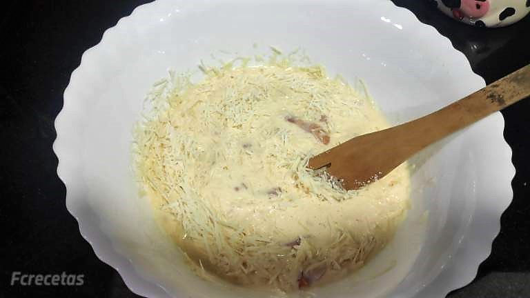 bacón y queso añadido a los huevos batidos en un recipiente