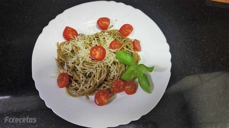 un plat blanc amb espaguett al pesto i tomàquets cherrry