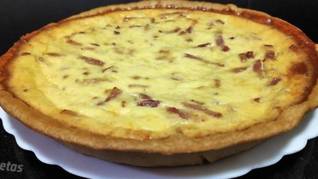 quiche lorraine en un plato blanco sobre fondo negro