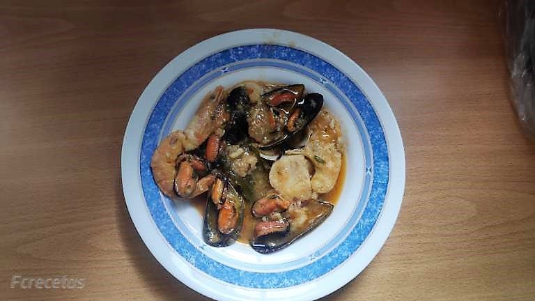 zarzuela de pescado en un plato sobre fondo de madera