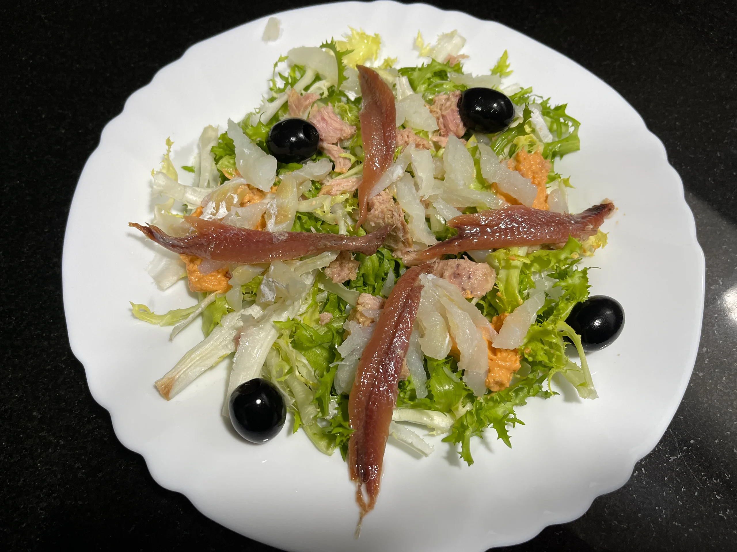 un plato con xatonada es una ensalada con escarola, anchoas, bacalao, olivas y salsa
