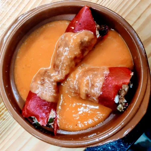 una cazuela de barro con tres pimientos del piquillo en salsa
