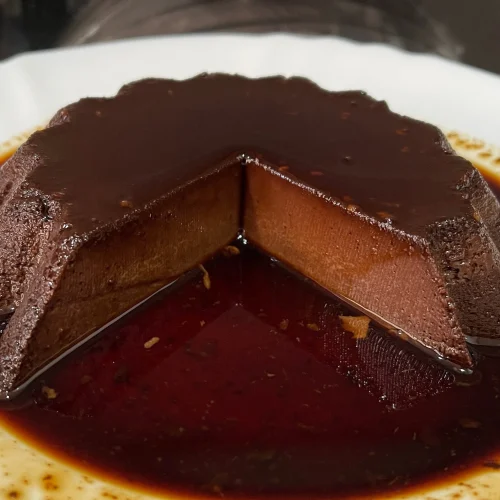 un flan de chocolate con una porción cortada en un plato blanco