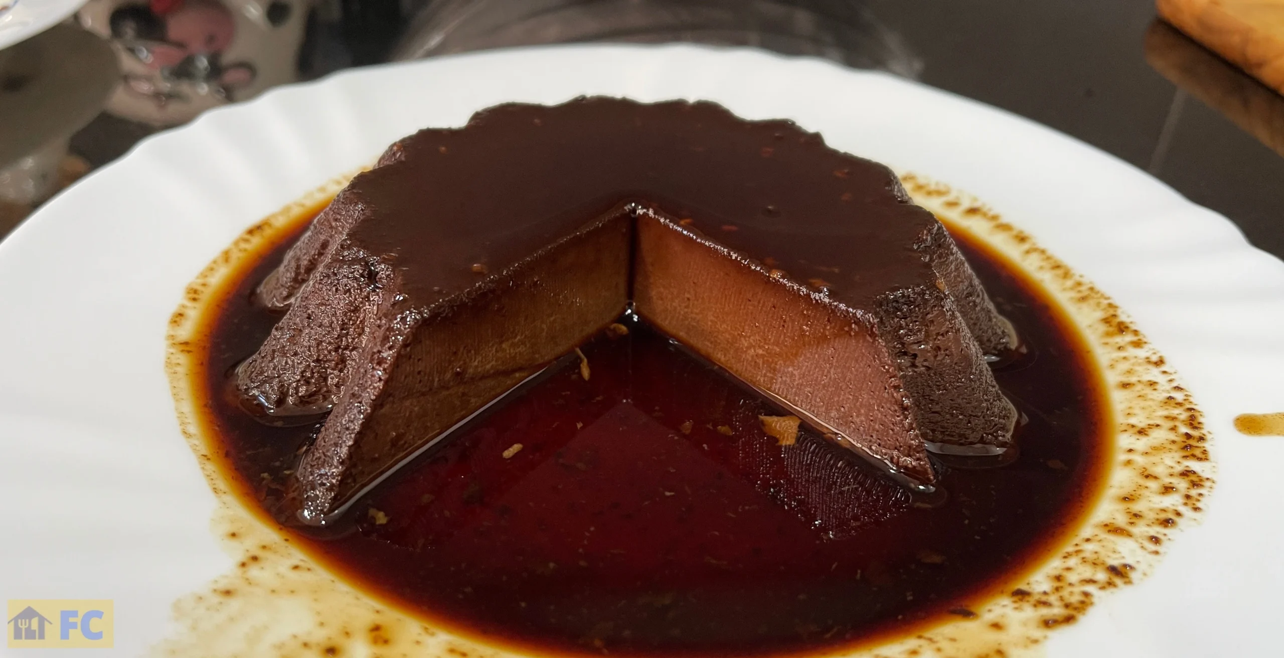 un flam de xocolata amb una porció tallada en un plat blanc