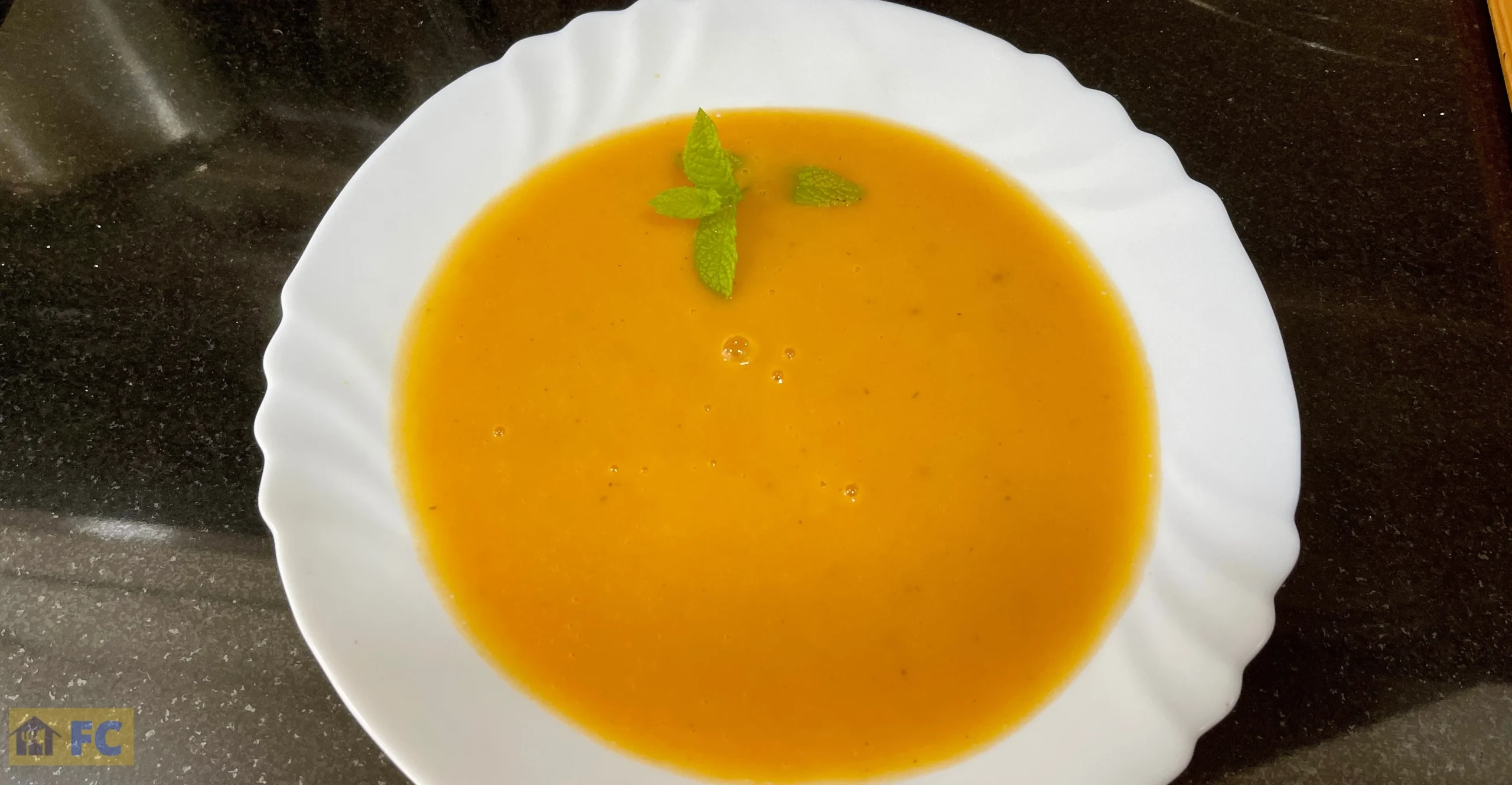 un plato de sopa de tomate con una ramita de menta