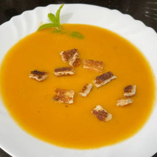 sopa de tomate con picatoste y una ramita de hierbabuena