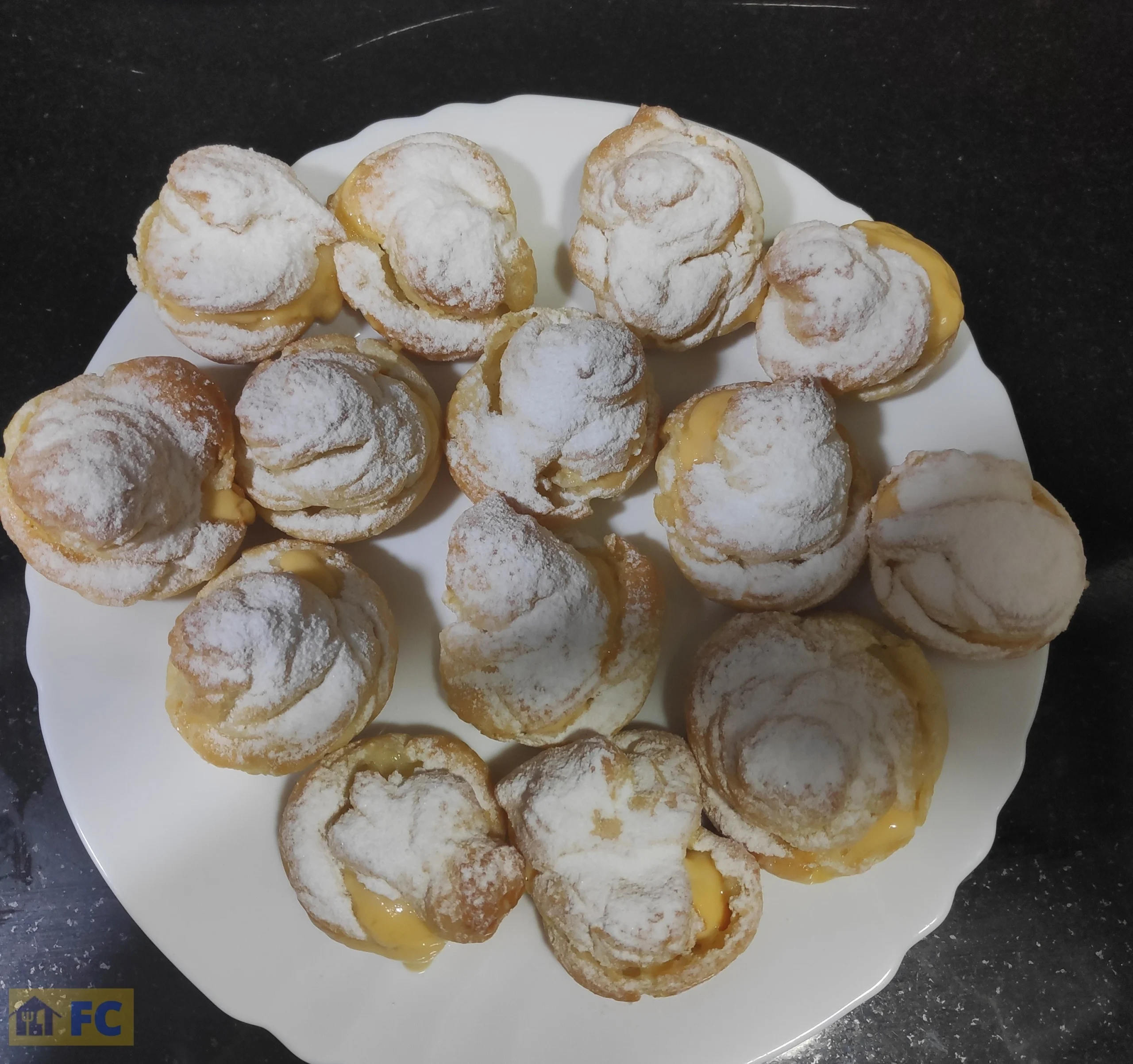 Un plato con lionesas o profiteroles de crema con azúcar glas
