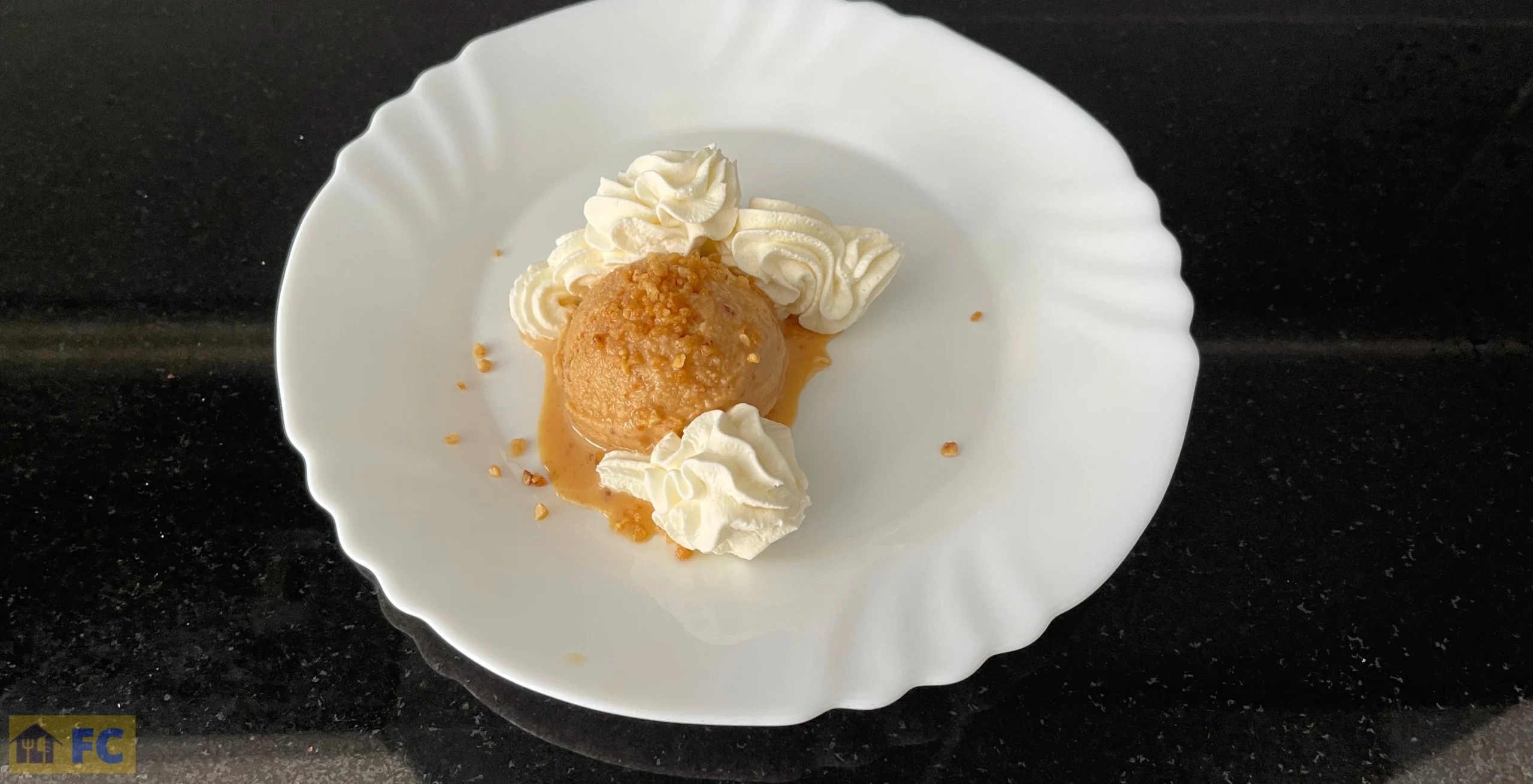 un plat amb una bola de torró xixona, crocanti d'ametlles i nata