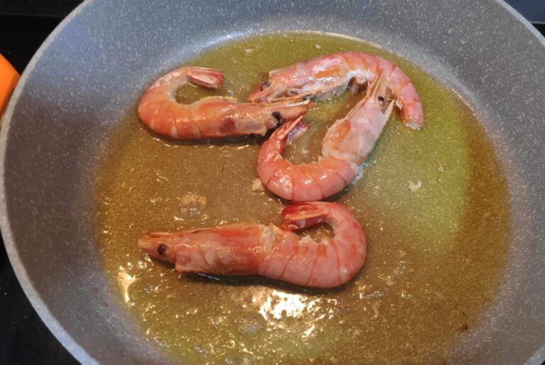 sofriendo gambas en la sartén para elaborar la fideuá