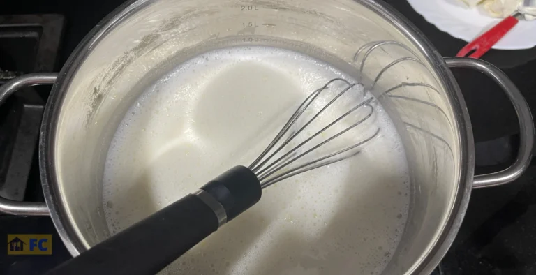 una cazuela con leche y un batidor manual de varillas