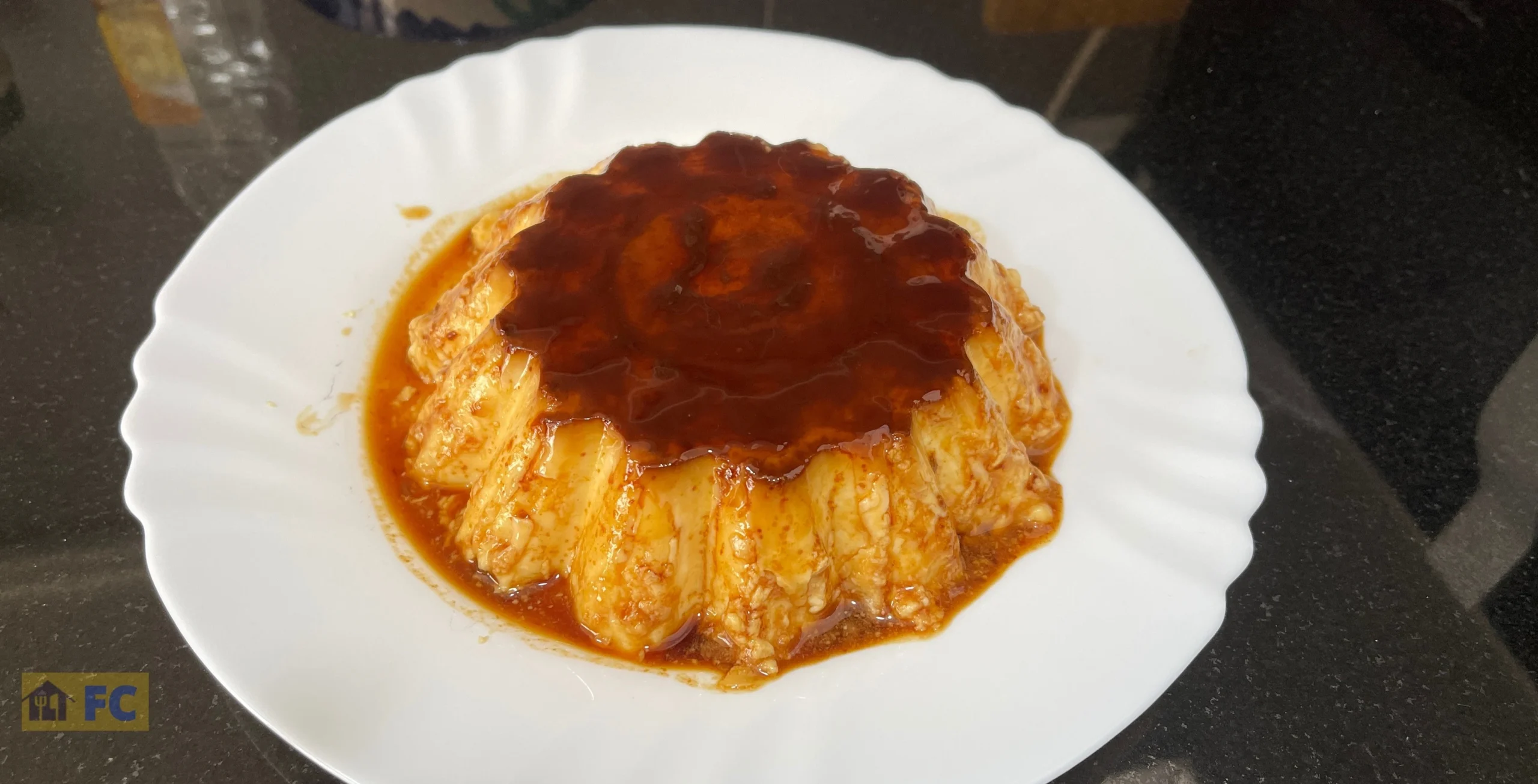 Flan de queso casero en un plato blanco sobre fondo negro