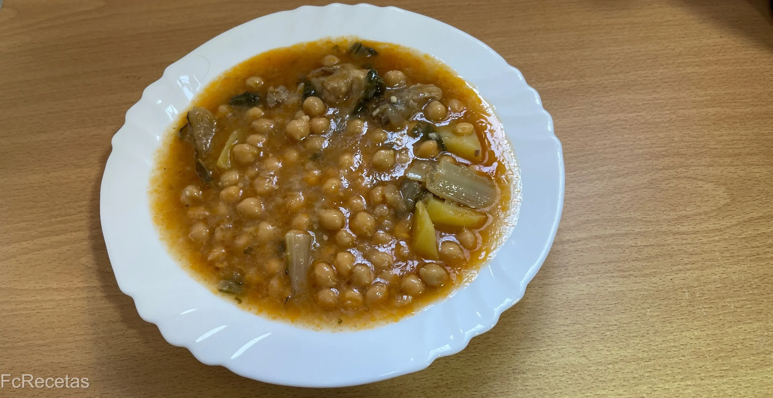 un plato con garbanzos con acelgas y costillas
